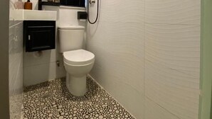 Une petite salle de bain avec des toilettes, un miroir et une douche.
