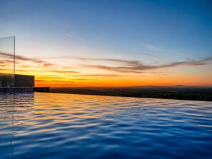 A pool with a view of a sunset over a landscape.