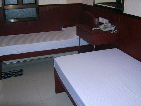 A hotel room with two single beds, a desk with a telephone, and a pair of shoes on the floor.