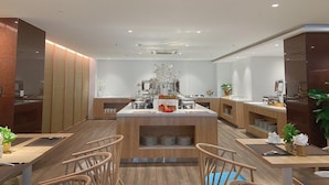A modern hotel lobby with a central bar area, wooden flooring, and seating arrangements.