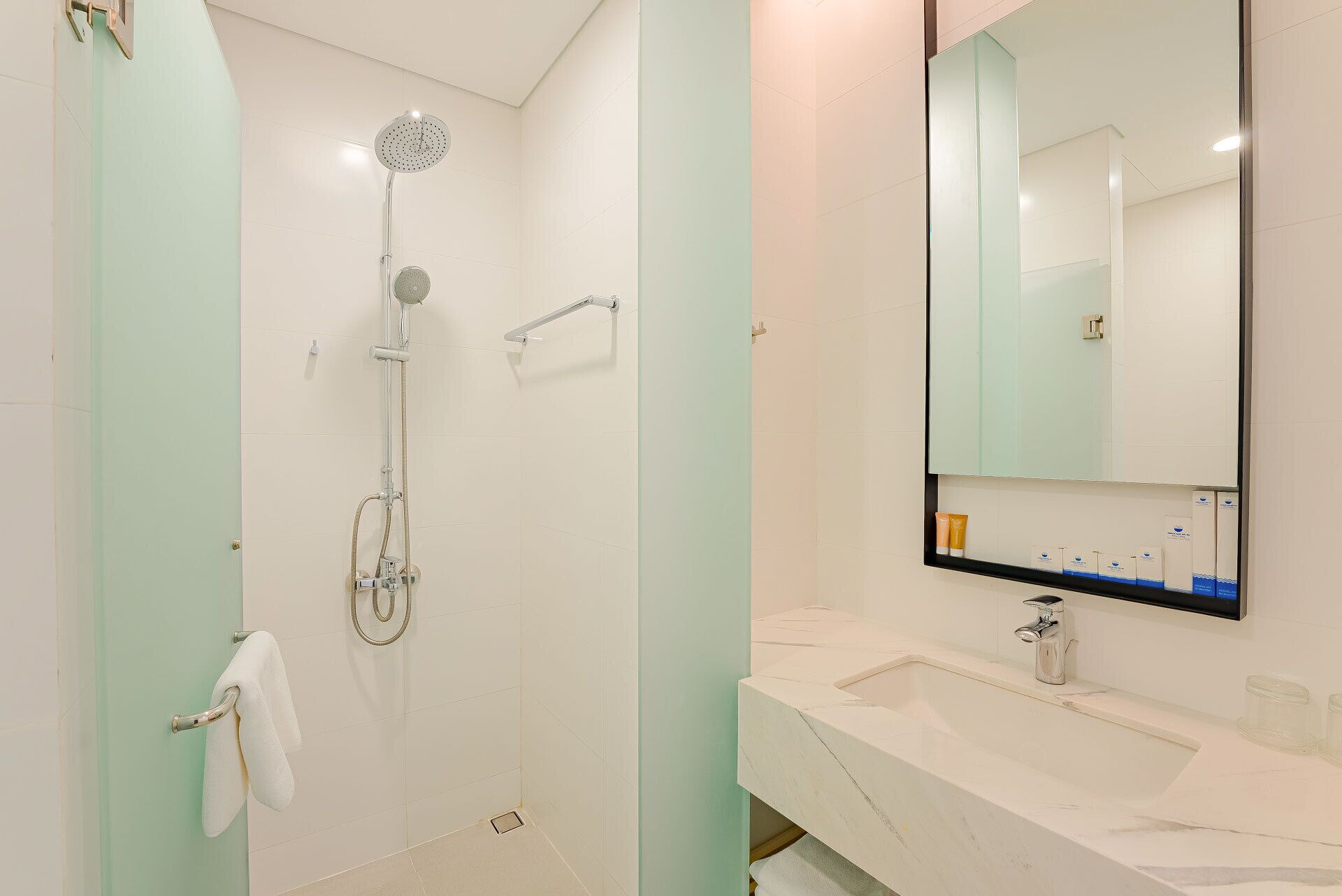 A modern bathroom with a shower, a sink, and a large mirror.