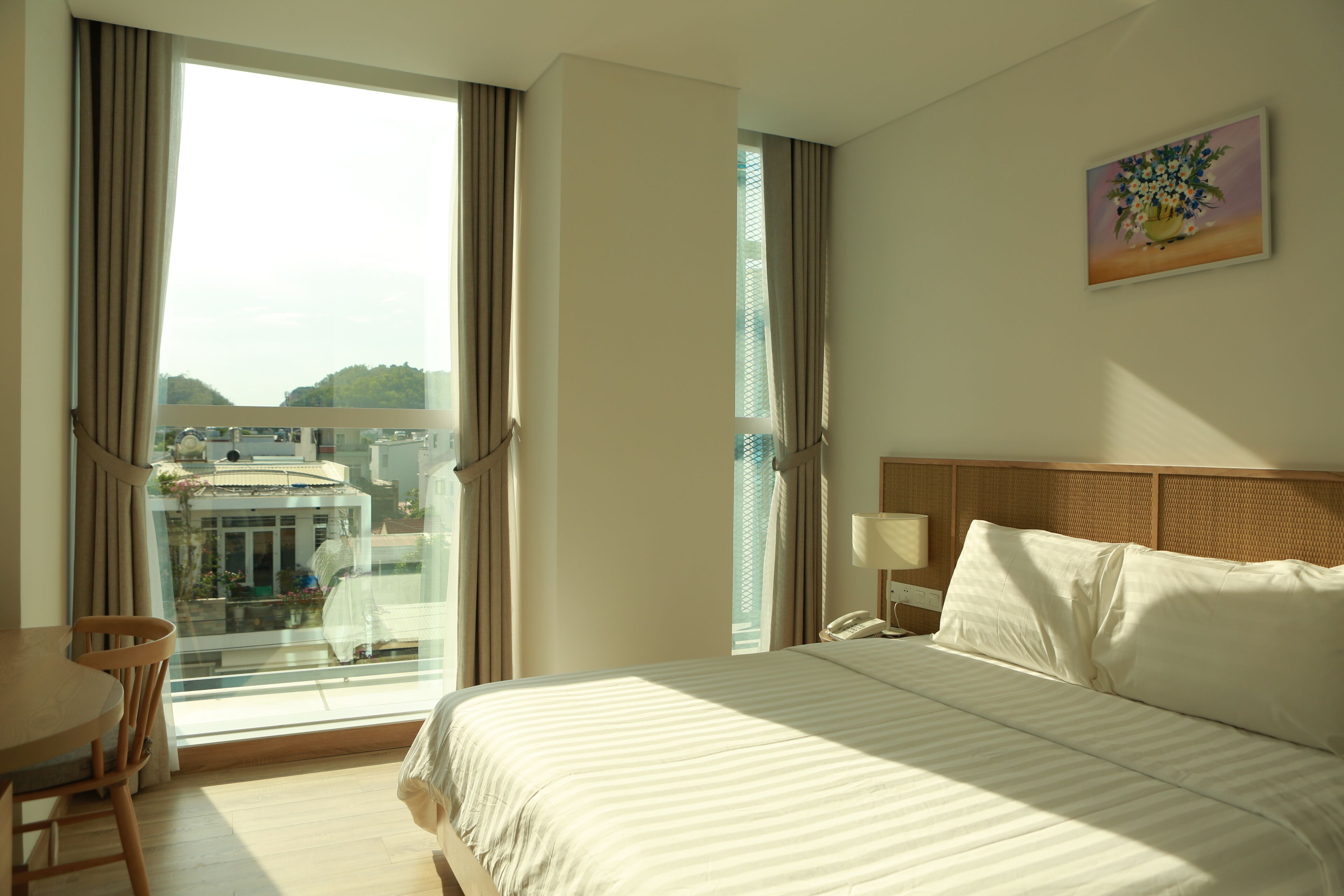 A hotel room with a large bed, a desk, and a window with curtains.