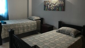 A bedroom with two single beds, a nightstand, and a wall-mounted artwork. - CASA BELLA 2 YOUR PIECE OF PARADISE (san andres isla)