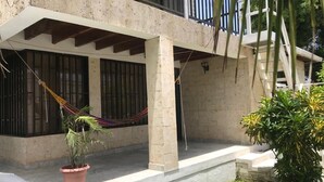 A building with a concrete facade, a balcony with metal railings, and a potted plant in the foreground. - CASA BELLA 2 YOUR PIECE OF PARADISE (san andres isla)