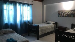 A room with two beds, a desk, and a painting on the wall. - CASA BELLA 2 YOUR PIECE OF PARADISE (san andres isla)