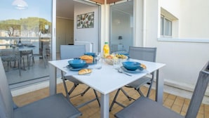 Een eetgedeelte met een tafel gedekt voor twee personen, met blauwe kommen, een fles sinaasappelsap en een mand met fruit.