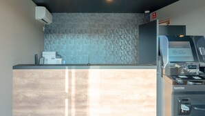 A hotel reception area with a modern design, featuring a reception desk, a digital display, and a security camera. - HOTEL R9 The Yard Isezaki (Isesaki)