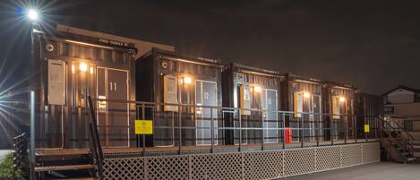 A row of numbered cabins with metal railings and a staircase leading up to the entrance.
