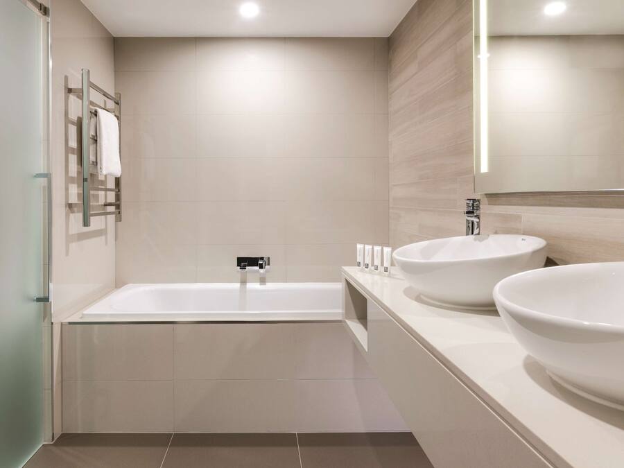 A modern bathroom with a glass-enclosed shower, a freestanding bathtub, and two large white sinks.