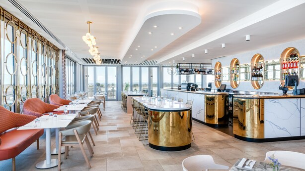 A modern restaurant with a central bar, high ceilings, and large windows offering city views. - Vibe Hotel Subiaco Perth (Subiaco)