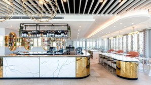 A modern bar area with a marble counter, gold accents, and a ceiling with geometric lighting. - Vibe Hotel Subiaco Perth (Subiaco)