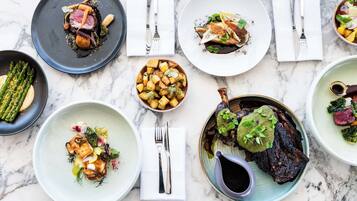A variety of dishes on a marble table, each with different garnishes and sauces.