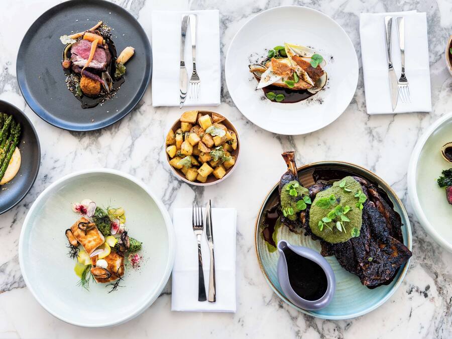 A variety of dishes on a marble table, each with different garnishes and sauces.