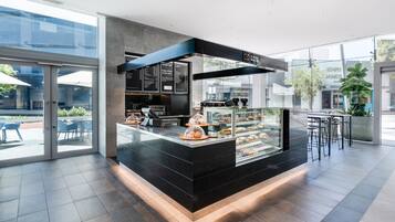 A modern café with a glass display case, a menu board, and seating area.