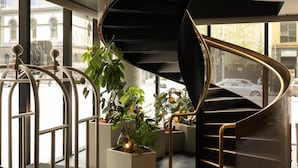 A modern interior with a spiral staircase, large windows, and potted plants. - Quincy Hotel Melbourne (Melbourne)