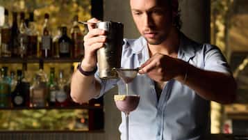 A bartender pouring a drink into a martini glass.