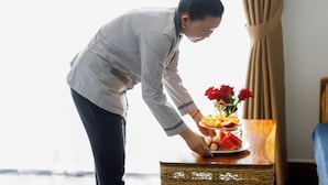 Une personne qui prépare une présentation de fruits et de fleurs sur une table.