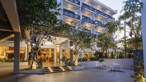 Une cour d’hôtel avec un espace salon abrité, des plantes en pot et un escalier menant à l’entrée.