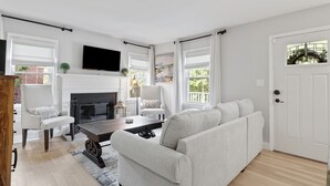A living room with a fireplace, a sofa, a coffee table, and a TV mounted on the wall.
