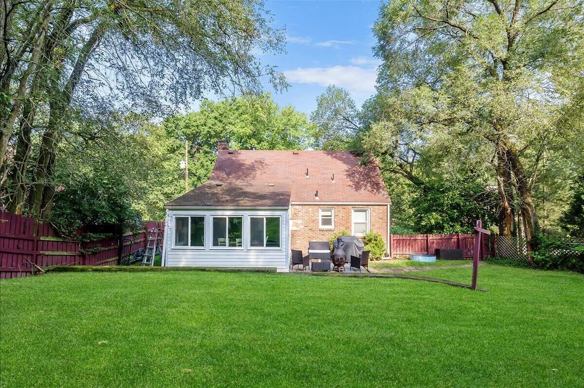 A single-story house with a brick exterior, a covered patio with outdoor furniture, and a fenced yard.