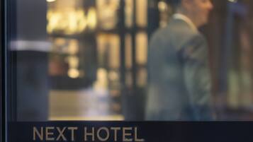 A blurred interior of a hotel with a sign reading "NEXT HOTEL".