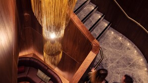 A modern interior with a curved staircase, a seating area, and a decorative light fixture. - Next Hotel Melbourne, Curio Collection by Hilton (Melbourne)