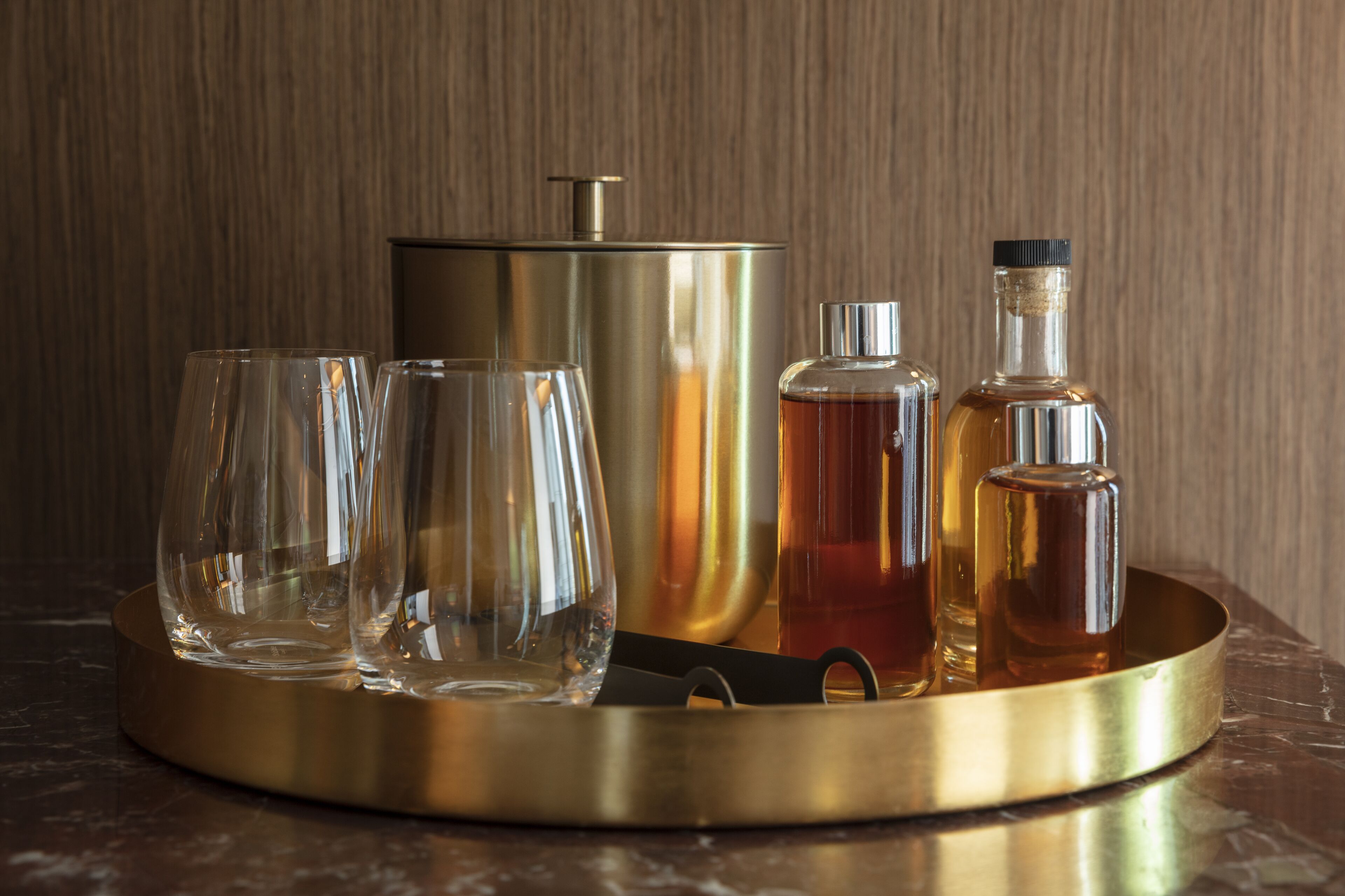 Un plateau avec un récipient métallique, deux verres et deux bouteilles.