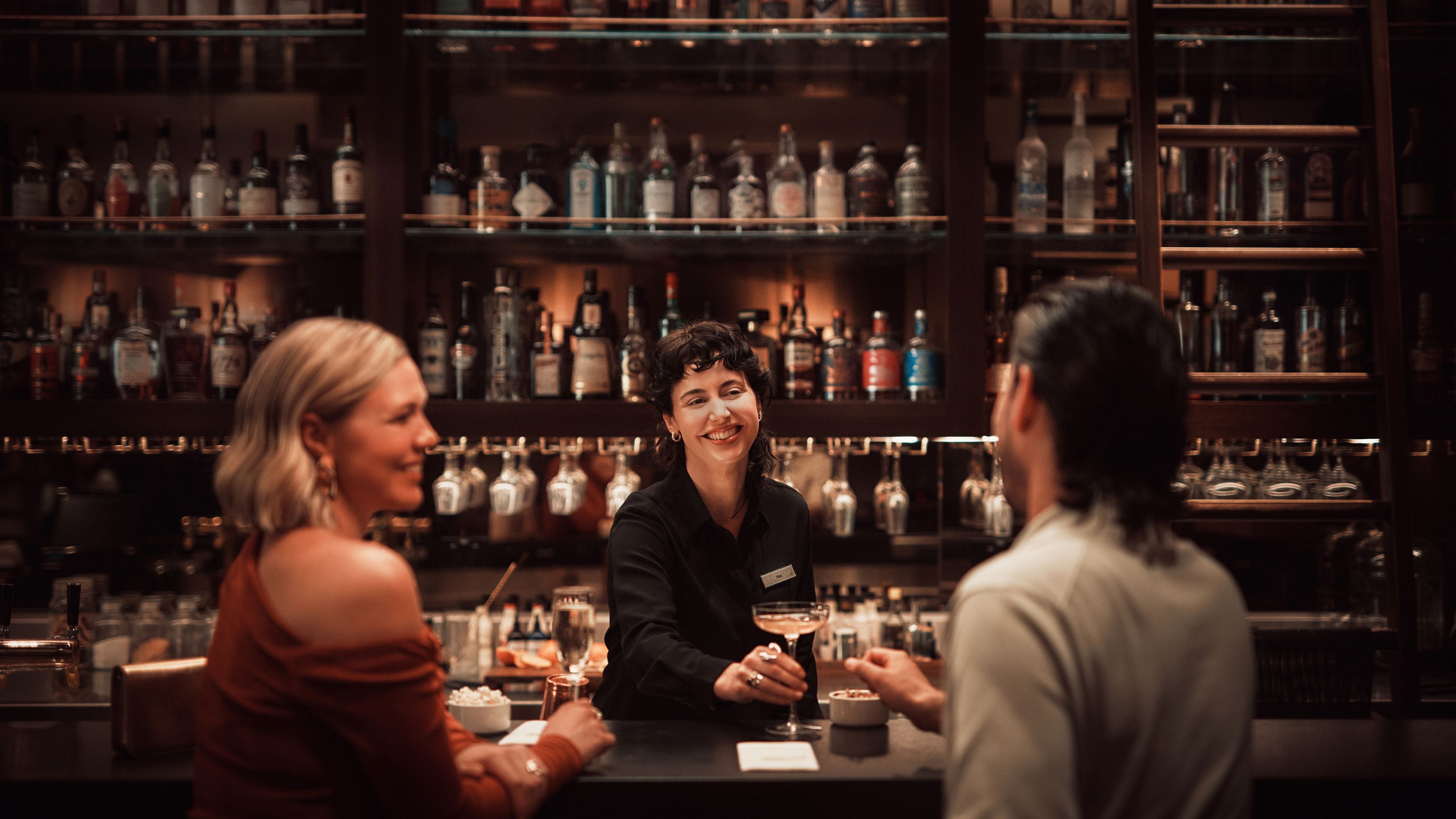 Un bar avec des étagères remplies de bouteilles et de verres.