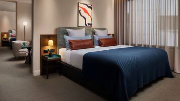 A hotel room with a large bed, a bedside table with a lamp, a chair, and a mirror.