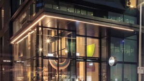 A modern hotel entrance with glass doors, a visible entrance sign, and a clear view of the interior through the glass. - Next Hotel Melbourne, Curio Collection by Hilton (Melbourne)