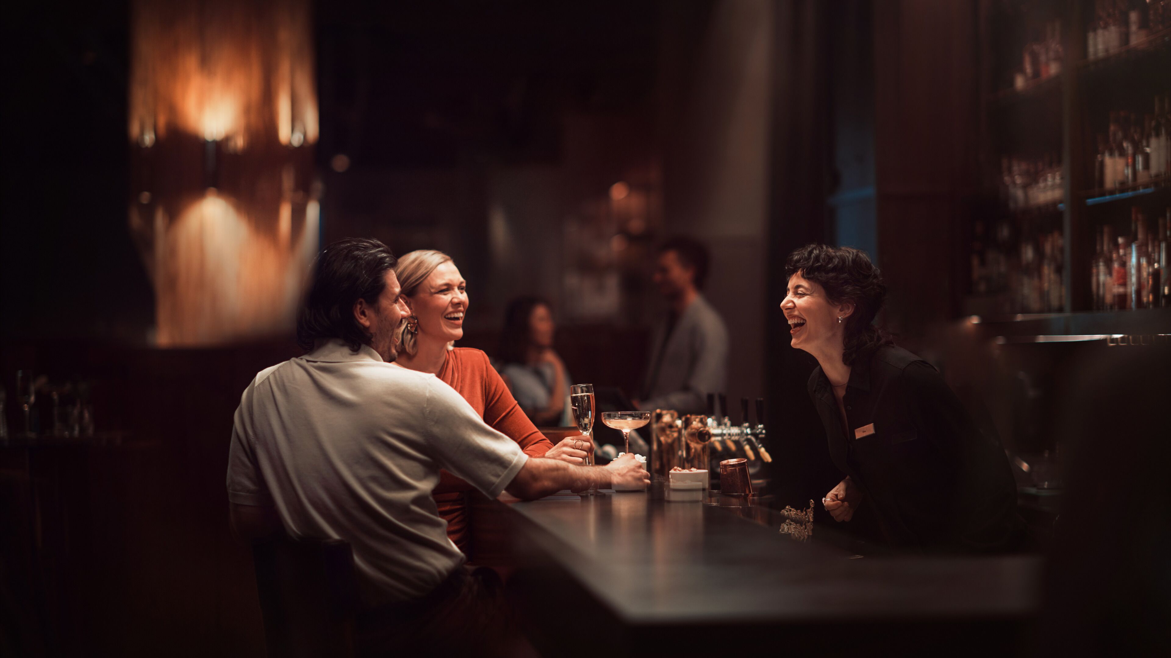 A bar area with a bar counter, bottles, and glasses.