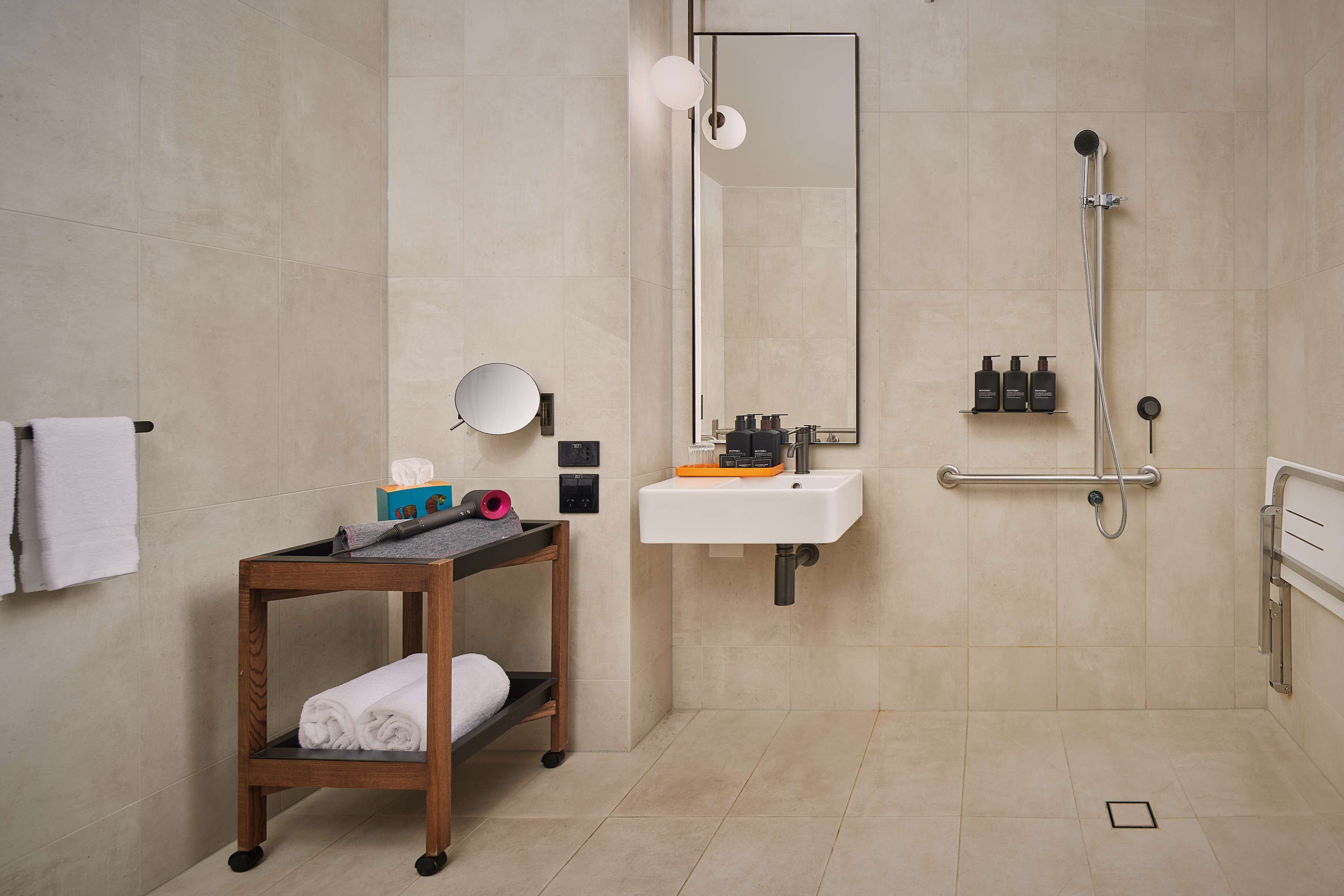 A modern bathroom with a wooden vanity, a large mirror, a sink, and a shower.