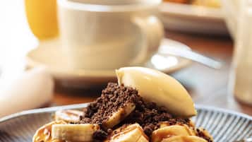 Un plato de postre con plátanos y migas de chocolate.