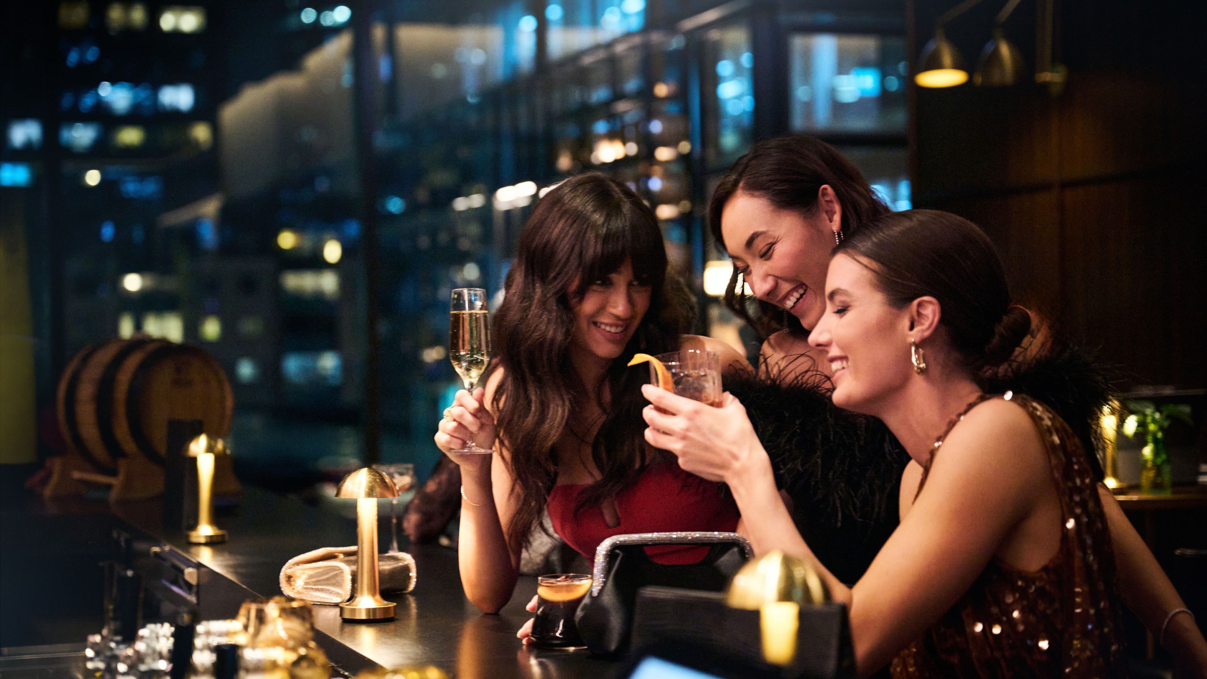 A bar setting with a city view, a candle, and a bottle of wine.