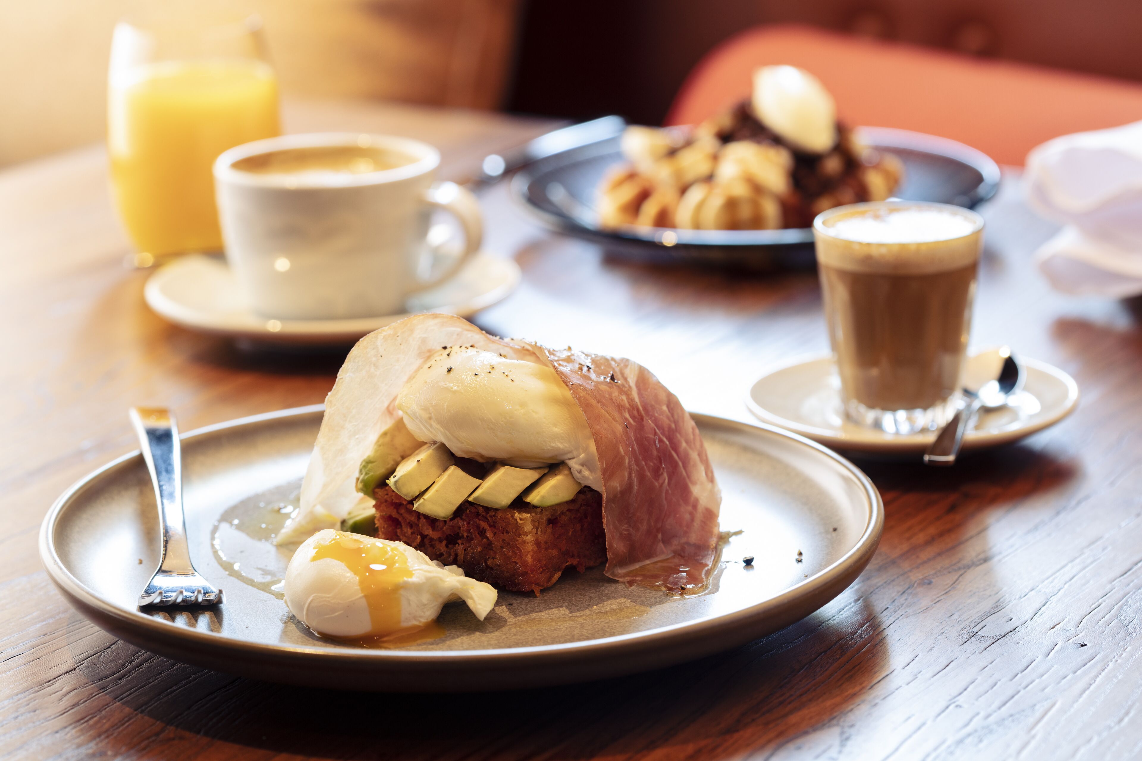 A breakfast setting with a plate of food, a cup of coffee, and a glass of juice.