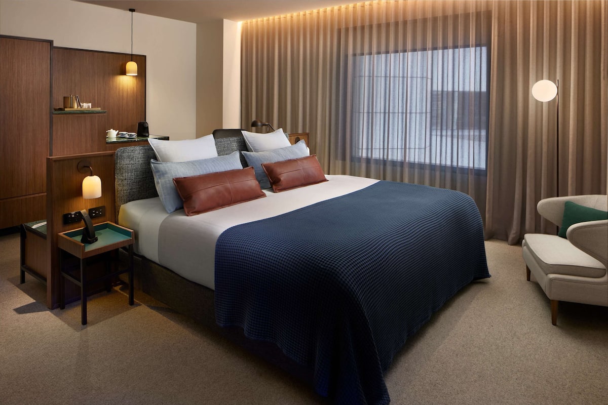 A modern hotel room with a large bed, bedside tables, a desk, and a chair.