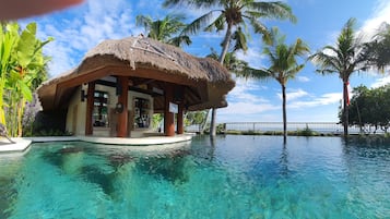 Una piscina al aire libre, sombrillas, sillones reclinables de piscina