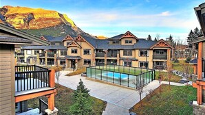 Un complejo turístico con varias construcciones, una piscina central y un paisaje montañoso.