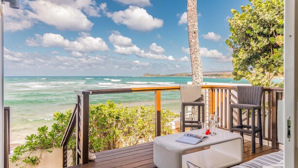 Eine Terrasse mit Blick auf das Meer, Holzgeländer und Gartenmöbel.
