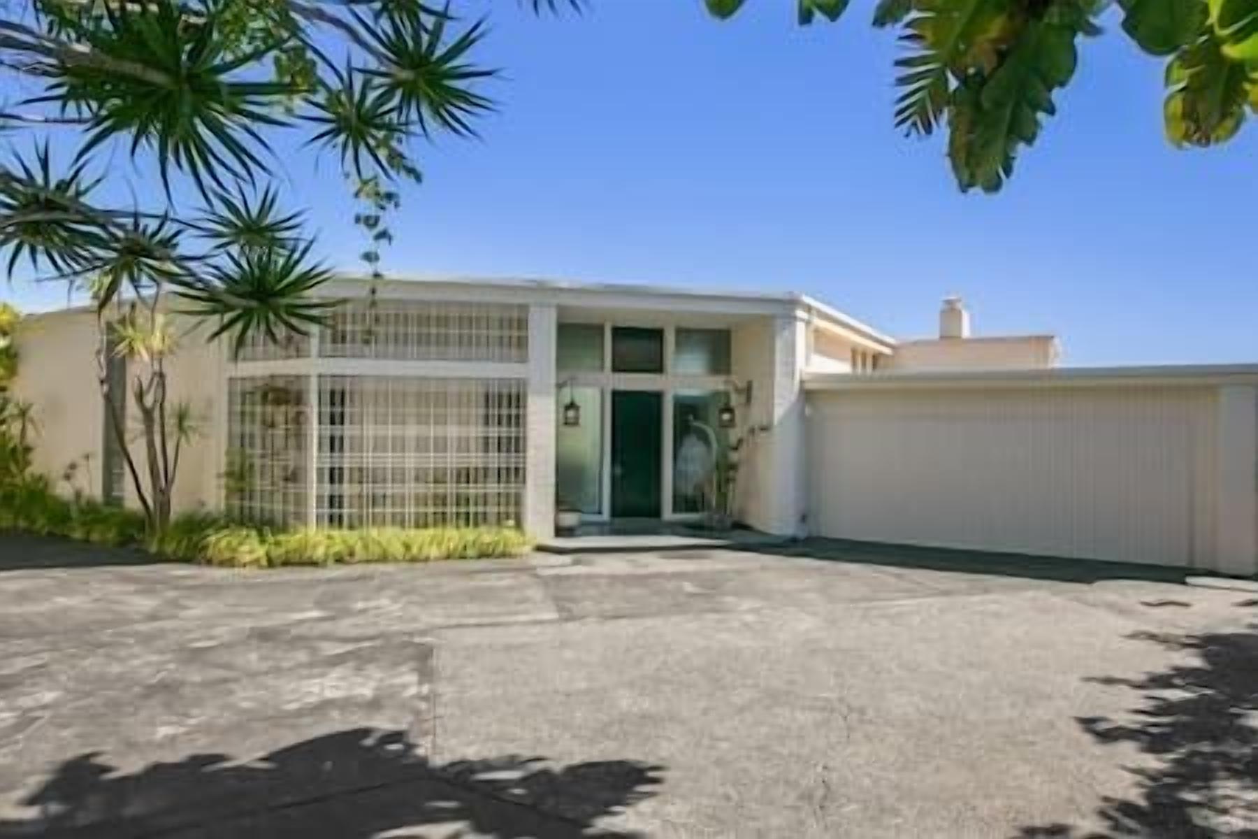 A two-story building with a gated entrance, a flat roof, and a concrete driveway.
