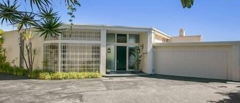 A two-story building with a gated entrance, a flat roof, and a concrete driveway.