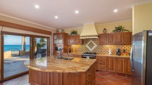 A kitchen with wooden cabinets, a granite countertop, and a view of the ocean. - Rare Beachfront Steps to Sand/Paddleboards and Bikes  (Loreto)
