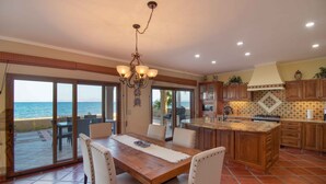 A spacious kitchen with a large island, sliding glass doors to a patio, and a view of the sea. - Rare Beachfront Steps to Sand/Paddleboards and Bikes  (Loreto)