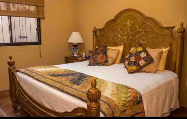 A bedroom with a wooden bed, a nightstand with a lamp, and a window with blinds. - Rare Beachfront Steps to Sand/Paddleboards and Bikes (Loreto)