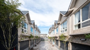 A row of brick buildings with uniform windows and shutters, a tiled walkway, and a clear sky. - Yilan East Hotel (Jiaoxi)