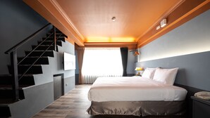 A bedroom with a large bed, a wooden staircase, and a view of the outdoors. - Yilan East Hotel (Jiaoxi)