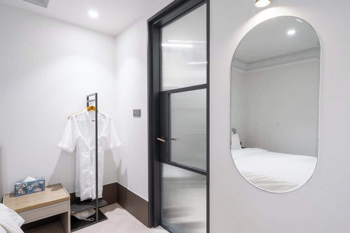 Habitación de hotel con cama, armario, espejo y una mesita con caja de pañuelos.