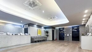 A hotel reception area with a modern design, including a reception desk, seating area, and an elevator. - Brown Dot Hotel Busan Sajik Stadium (Busan)