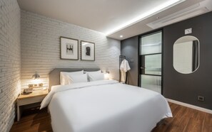 Una habitación de hotel moderna con pared de ladrillo, una cama grande, un armario y un espejo.