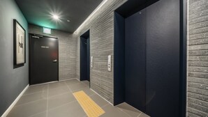 A hallway with two elevators, a tactile paving strip, and a door labeled "STAFF ONLY". - Brown Dot Hotel Busan Sajik Stadium (Busan)